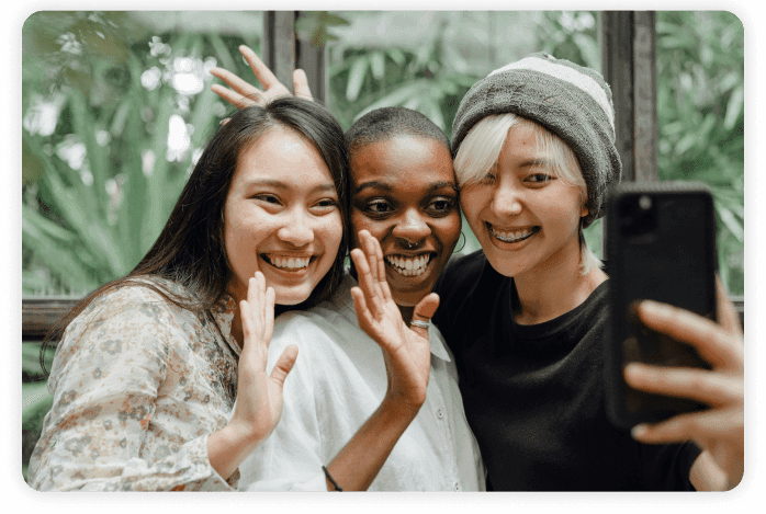 Three women holding a phone up for a picture